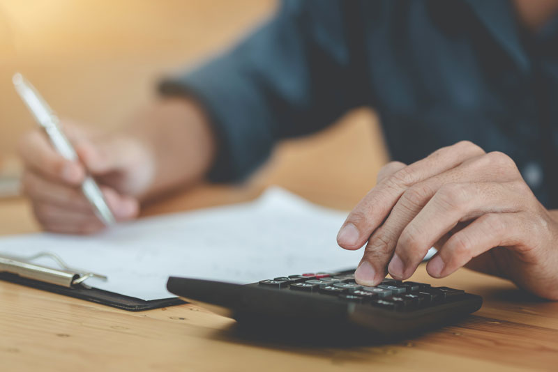 Man using calculator to determine the cost of dental implants.