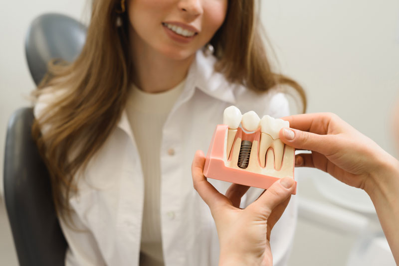 Dental Patient Getting Shown A Dental Implant Model During Her Consultation in Holbrook, MA